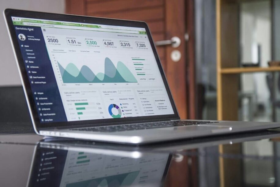 portátil sobre mesa de cristal. pantalla muestra gráficas empresariales.